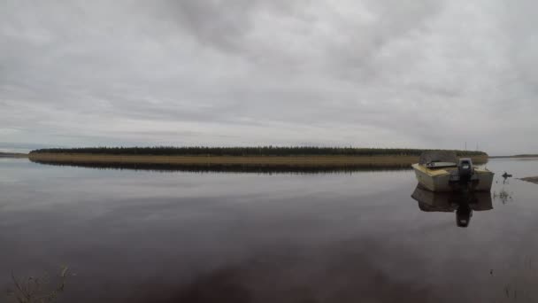在雅库提亚的塔加河流域的河岸上，水流的快速运动和多云的天空，在山脉和松树林的背景下，用马达绑住铁苏船. — 图库视频影像