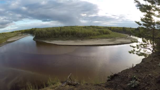 Video timelapse van de stroom van de noordelijke rivier in Yakutia op een beurt van twee banken met gras zand en bomen. Dikke wolken lopen over de hemel en werpen schaduwen op het ondiepe water en de zanderige bodem. — Stockvideo