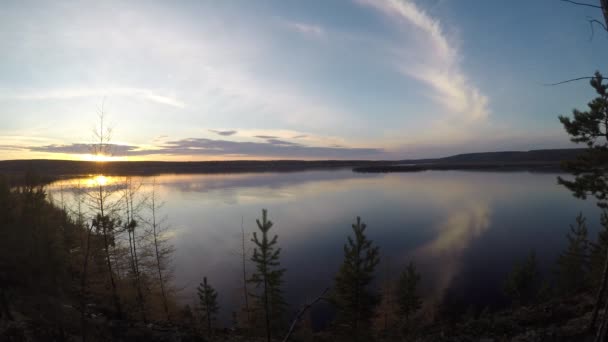 Timelapse panoramic view of the bright sun at sunset coming out of the clouds and throwing light on the yellow autumn spruce on the banks of the river in tage forest in front of Yakutia. — Stock Video