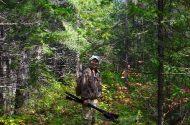 Gözlük ve şapka ile Yakut kız turist sıcak elinde olta lar ve seyahat için bir sırt çantası ile Yakutistan vahşi taiga bir orman izi üzerinde durdurma gülümsüyor.