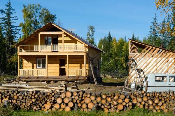 A new private cottage of yellow pine logs stands among spruce forests and wild forest firewood in the taiga of Yakutia, next to the remains of an iron garbage truck in the village of ulus Suntar.