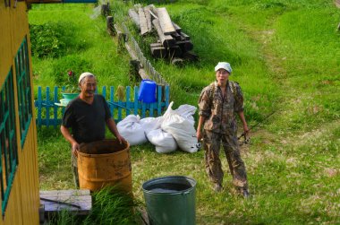 Gülümseyen yaşlı adam Yakut ve dişli ile genç bir Asyalı kız balıkçı Yakutia Kuzey köyünde özel bir evin bahçesinde bulunmaktadır.