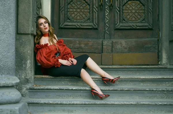 迷人的苗条的女人在红色优雅的衬衫和黑色裙子摆在楼梯上 时尚照片 — 图库照片