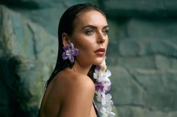 Portret atrakcyjna młoda kobieta z kolczyki w formie kwiatów tropikalnych przeciwko rock Obrazy Stockowe bez tantiem