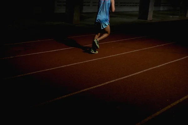Athletics people running on red running track at night