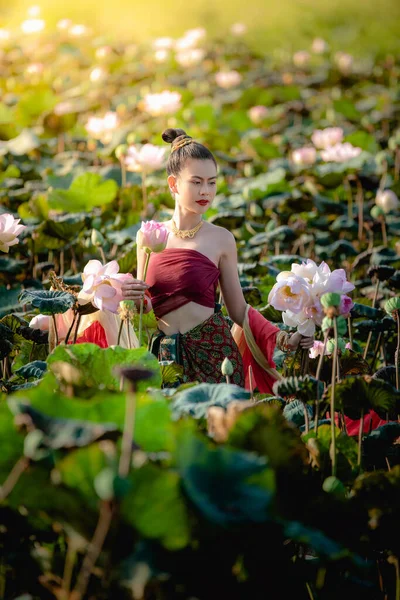 Asiatisk kvinna samlar lotus blommor och hon bär traditionella thailändska klänningar — Stockfoto