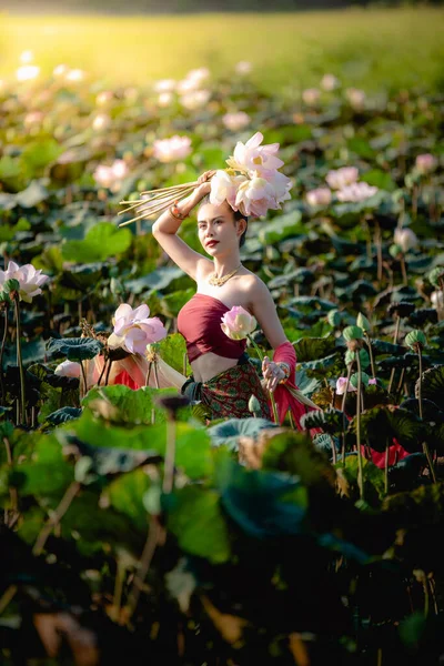 Asiatin sammelt Lotusblumen und trägt traditionelle thailändische Kleider — Stockfoto