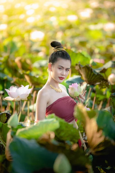 Азиатка собирает цветы лотоса и носит традиционные тайские платья — стоковое фото