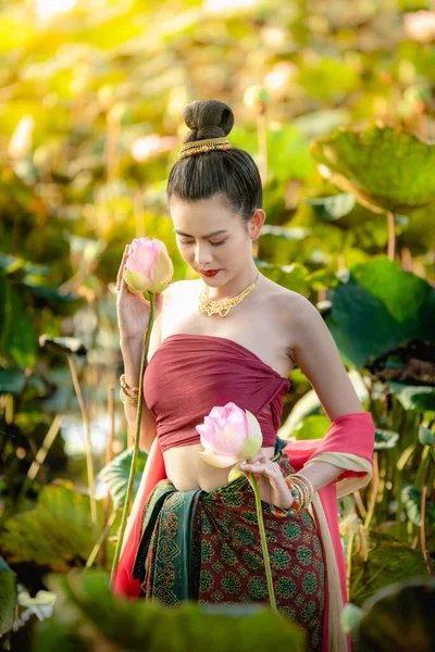 Asiatisk kvinna samlar lotus blommor och hon bär traditionella thailändska klänningar — Stockfoto