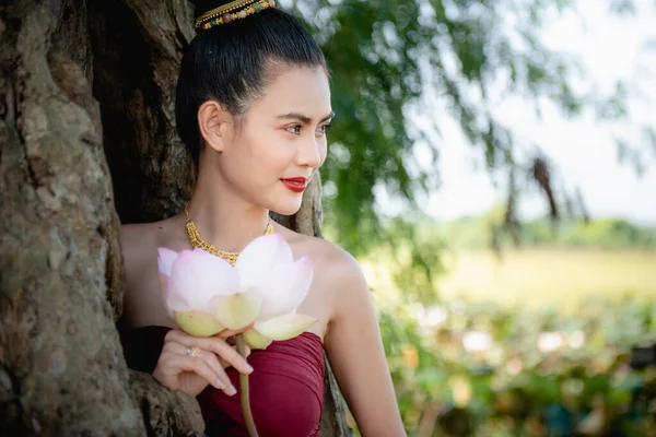 Asian woman collecting lotus flowers and she wear Traditional Thai dresses