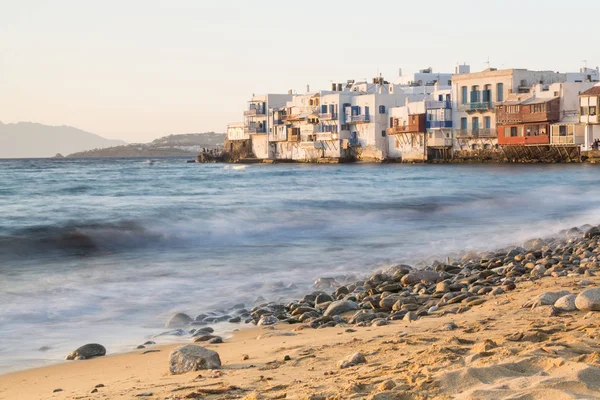 MYKONOS, GREECE - MAY 2018: View over the old Mykonos town district Little Venice with stony beach and sea on the foreground. Long exposure shot, water movement effect — Stock Photo, Image