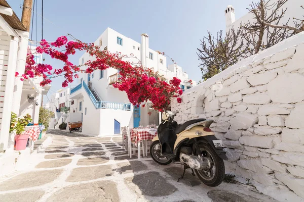 Mykonos, Yunanistan - Mayıs 2018: Eski Arnavut kaldırımlı sokakta Mykonos town bölgesine Küçük Venedik, Restoran ve çiçeği çalı üzerinden görünüm. Retro scooter ön plan üzerinde seyir