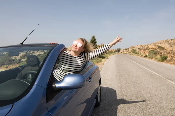 Jovem mulher loira dirigindo carro de aluguel azul conversível sem telhado na estrada da montanha na ilha de Naxos, Grécia — Fotografia de Stock