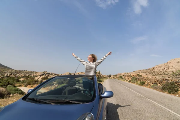 Jovem mulher loira dirigindo carro de aluguel azul conversível sem telhado na estrada da montanha na ilha de Naxos, Grécia — Fotografia de Stock