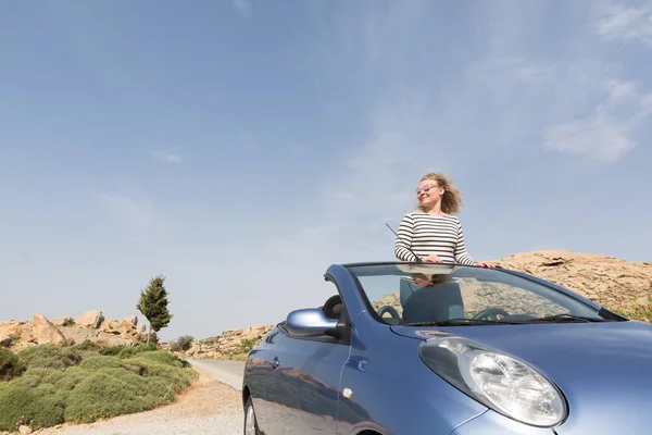 Jovem mulher loira dirigindo carro de aluguel azul conversível sem telhado na estrada da montanha na ilha de Naxos, Grécia — Fotografia de Stock