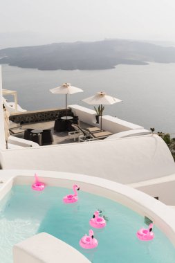 Santorini, Yunanistan - Mayıs 2018: volkan caldera, Yunanistan bakan Santorini Adası'nda lüks vila bir havuzda yüzme flamingo pembe oyuncak