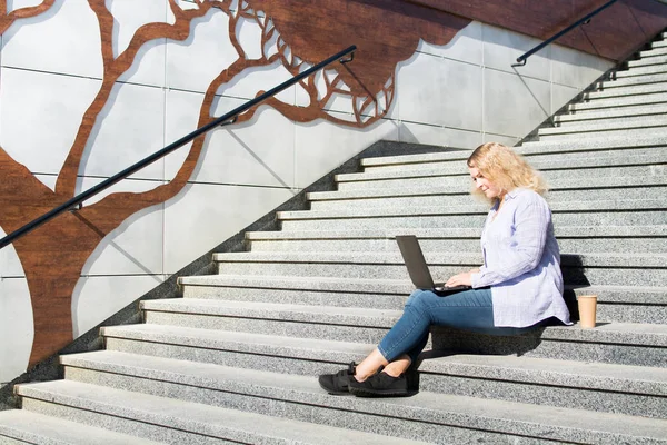 Νέοι blonge γυναίκα χρησιμοποιώντας το laptop της έξω. Κάθεται σε σκαλοπάτια, urban στυλ — Φωτογραφία Αρχείου