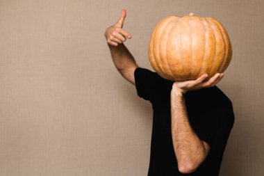 Siyah t-shirt büyük kabak yüzünü önünde tutan genç adam