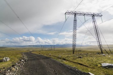 Boş toprak yol ve yüksek gerilim elektrik hatları ile İzlanda manzara.