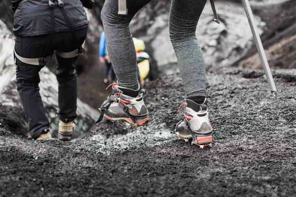 Group of tourists heading to the guided tour on the glacier, Iceland. Focus on special boots with crampons.