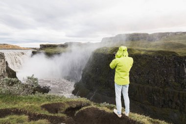 Dettifoss, İzlanda - Ağustos 2018: Adam uçurumun kenarına Vatnayokull Milli Parkı içinde şelale duran yeşil yağmurluk alarak resimdeki.