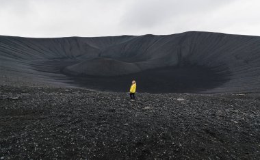 Genç kadın sarı yağmurluk ayakta Hverfjall alanında Myvatn, İzlanda yanardağ krater.