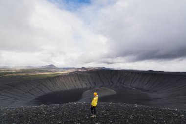 Genç kadın sarı yağmurluk ayakta Hverfjall alanında Myvatn, İzlanda yanardağ krater.