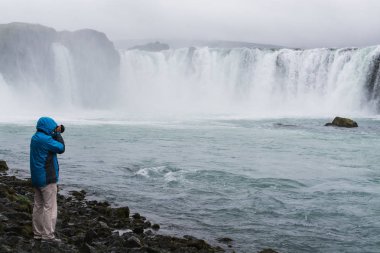 Fotoğrafçı içinde mavi ceket alma resim Godafoss şelale, İzlanda.