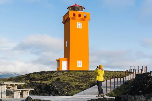 Sarı yağmurluk Svortuloft feneri, Snaefellsnes yarımada, İzlanda, gün batımını izlemek kadın.