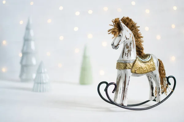 Rocking caballo de juguete con árboles de Navidad y llevó luces guirnalda en el fondo — Foto de Stock