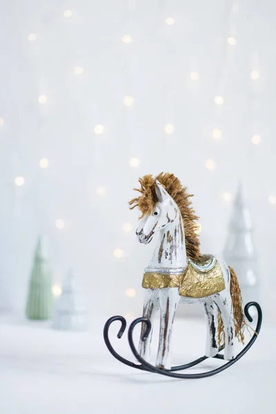 Rocking caballo de juguete con árboles de Navidad y llevó luces guirnalda en el fondo — Foto de Stock