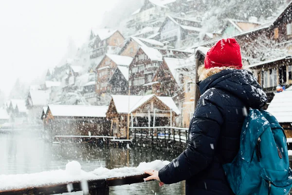 Kar fırtınası sırasında Avusturya lakefront Hallstatt eski şehirde manzarayı kırmızı şapkalı kadın.