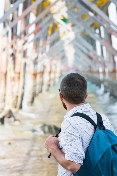 Jonge bebaarde blanke man staat onder houten pier aan de kust van Krabi, Thailand — Stockfoto