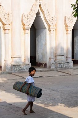 Bagan, Myanmar - Mart 2019: Bagan'da bambu mat taşıyan çocuk