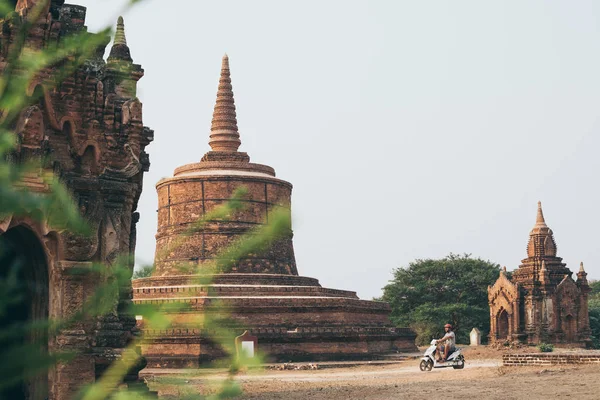 Man riding electric scooter towards temples and pagodas of ancient Bagan in Myanmar — Stock Photo, Image