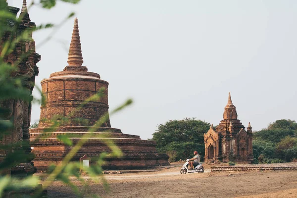 Man riding electric scooter towards temples and pagodas of ancient Bagan in Myanmar — Stock Photo, Image