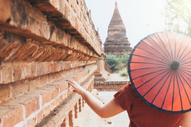 Myanmar'da pagoda ve antik Bagan tapınağına bakan kırmızı şemsiyeli kadın
