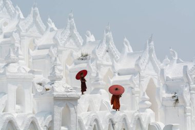 Mandalay, Myanmar - Nisan 2019: Myatheindan Pagoda'nın duvarlarında yürüyen kırmızı şemsiyeli Budist acemi rahipler