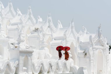 Mandalay, Myanmar - Nisan 2019: Myatheindan Pagoda'nın duvarlarında yürüyen kırmızı şemsiyeli Budist acemi rahipler