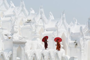 Mandalay, Myanmar - Nisan 2019: Myatheindan Pagoda'nın duvarlarında yürüyen kırmızı şemsiyeli Budist acemi rahipler