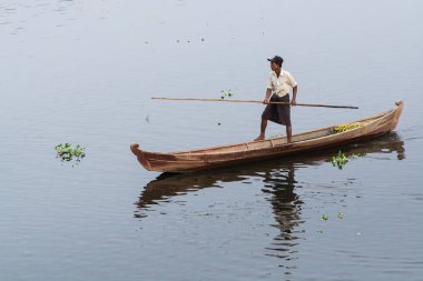 Nyaungshwe, Myanmar - Nisan 2019: Birmanyalı adam ahşap bir teknede kürek çekiyor