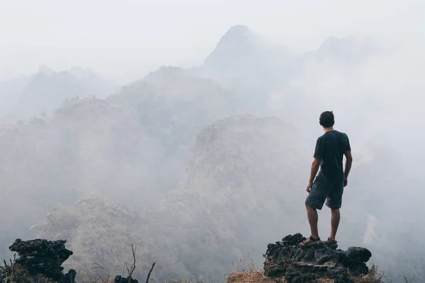 Mann steht auf dem Felsen mit Blick auf tropische Berge bei Sonnenaufgang neblig Morgen in hpa-an, myanmar — Stockfoto