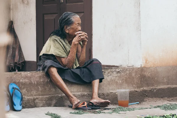 Luang Prabang, Laos-Mayıs 2019: eski Lao kadın ev verandasında oturur, düşünceli bir görünüm