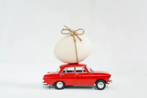 Coche de juguete rojo con huevo de gallina en el techo — Foto de Stock