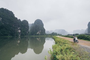 Ninh Binh eyaletinde kireçtaşı dağları arasında motosiklet sürme Adam, Vietnam.