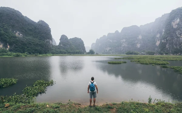 Caucasian man overlooking limestone mountains in Ninh Binh province, Vietnam. Cloudy day — Stock Photo, Image