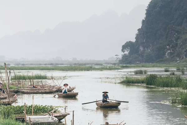 Ninh Binh, Vietnam - May 2019: Vietnamese woman in a wooden rowing boat going through Trang An nature park — Stock Photo, Image