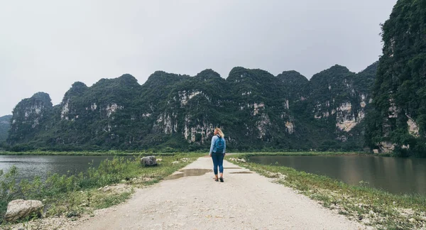Kaukasische blonde Frau zu Fuß in Richtung Kalksteinberge in der Provinz Ninh Binh, Vietnam — Stockfoto