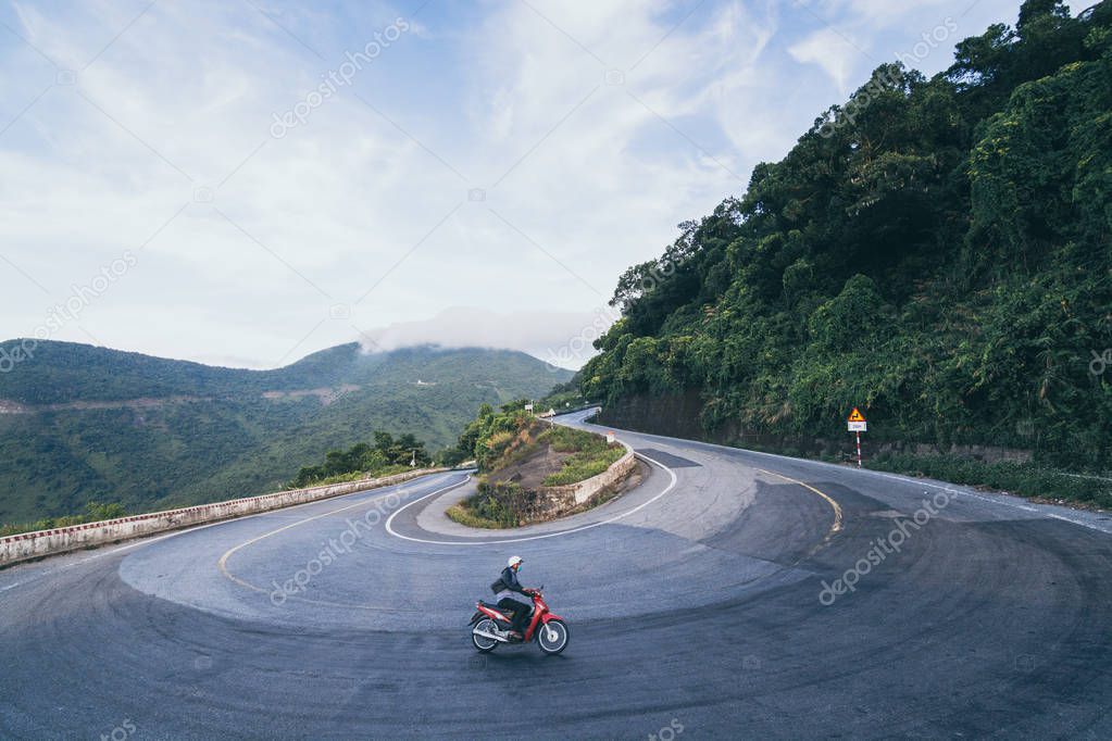 Man riding motorcycle on winding roads of Hai Van pass from Hue city to Hoi An, Vietnam