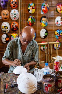 Hoi An, Vietnam - Haziran 2019: atölyesinde geleneksel Vietnam maskelerini boyayen adam